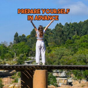 A woman standing on a scenic high wooden platform overlooking Oribi Gorge with her arms raised, with text reading Prepare Yourself In Advance, representing a tip to overcome fear of heights at Wild 5 Adventures.